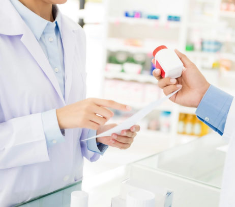 Male customers hand inspecting a medicine bottle while a pharmacist reviews the prescription emphasizing prescription drugs in Canada